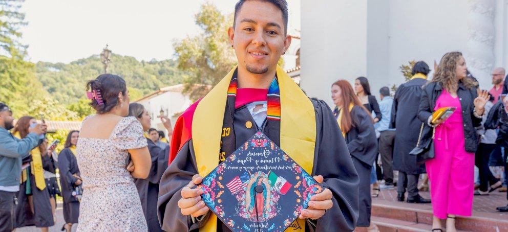 Student holding mortarboard with image of Virgen de Guadalupe at Latinx Graduate Celebration 2023