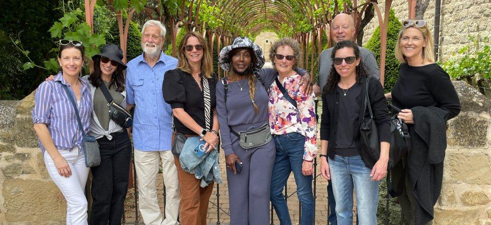 Nine alumni pose for a picture under vines in Spain